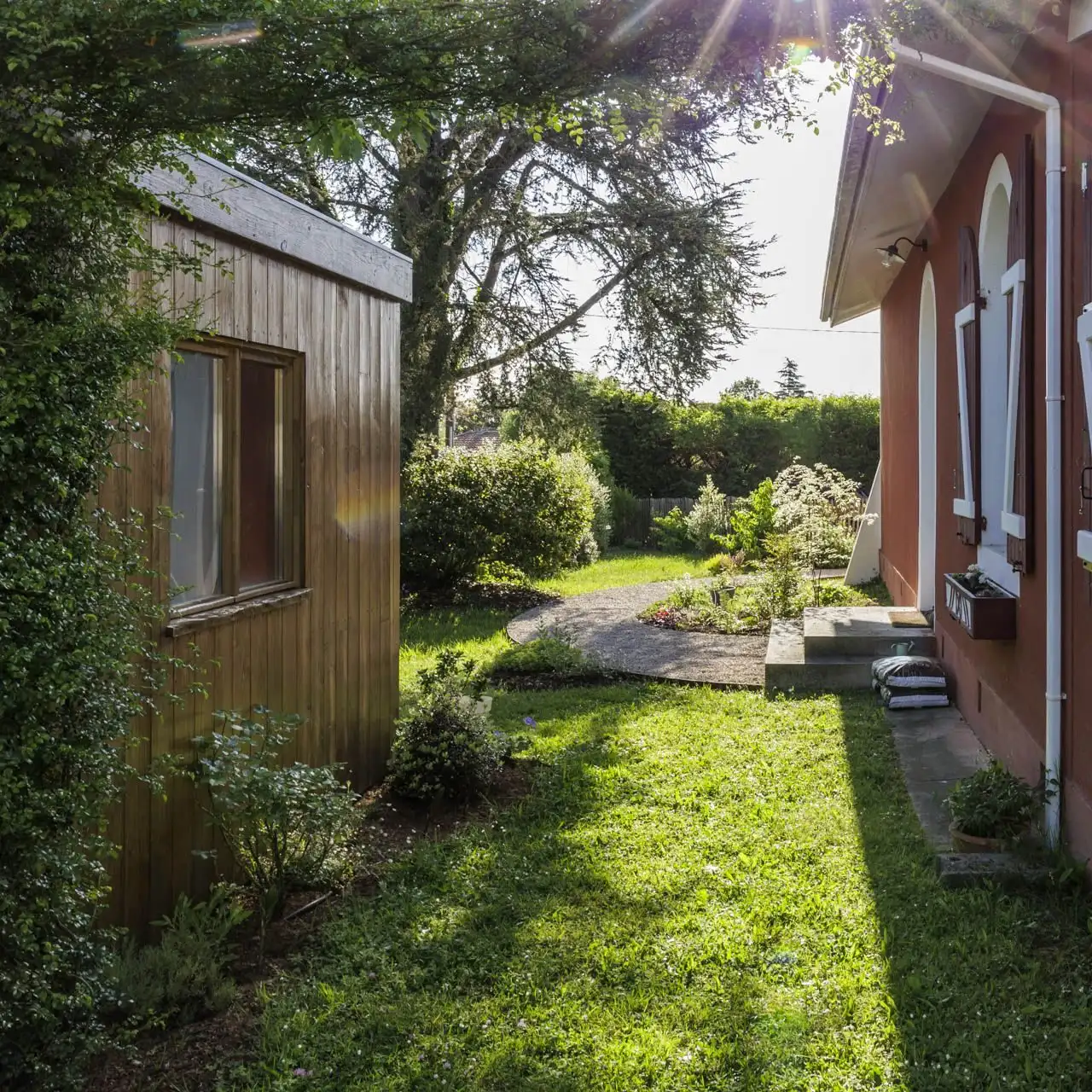 Sunny lawn between a wooden shed and the house