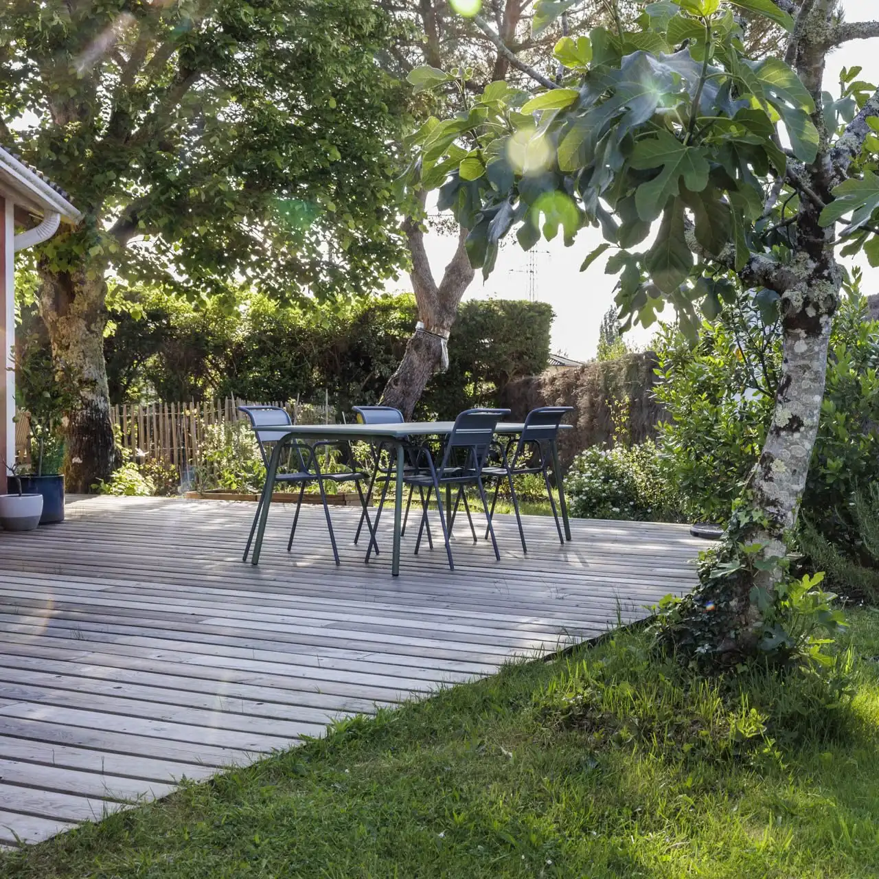 Garden with a wooden terrace and tall trees in Léognan