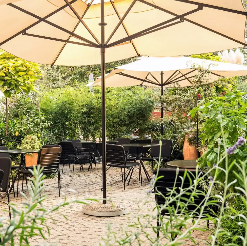 Restaurant terrace shaded by parasols, surrounded by plants